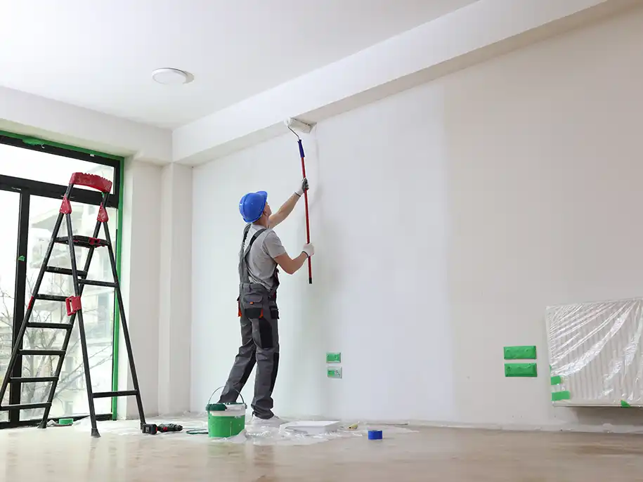 Mitarbeiter beim Streichen einer Wand mit weißer Farbe